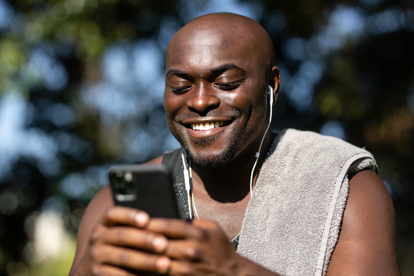 Persona sonriendo mientras mira la pantalla de su móvil
